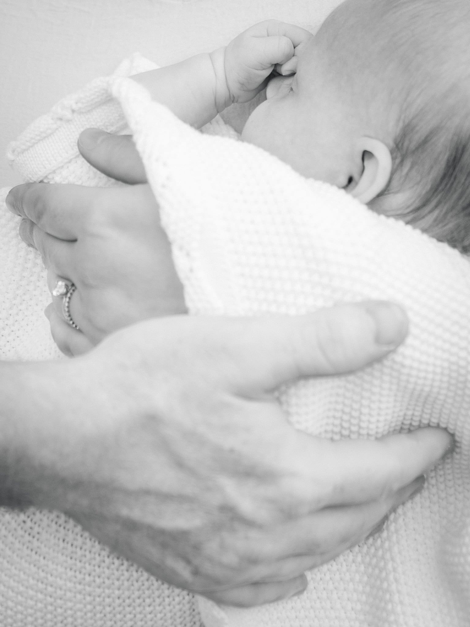 Black and white image from a newborn session of a sleeping baby wrapped in a blanket.
