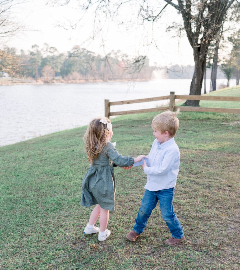 Brother and sister playing ring around the Rosie laughing together during a photo session.