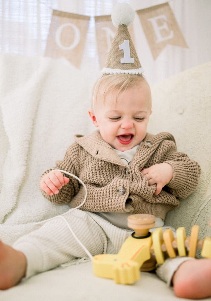 One year old smiling and celebrating his first birthday with milestone session.