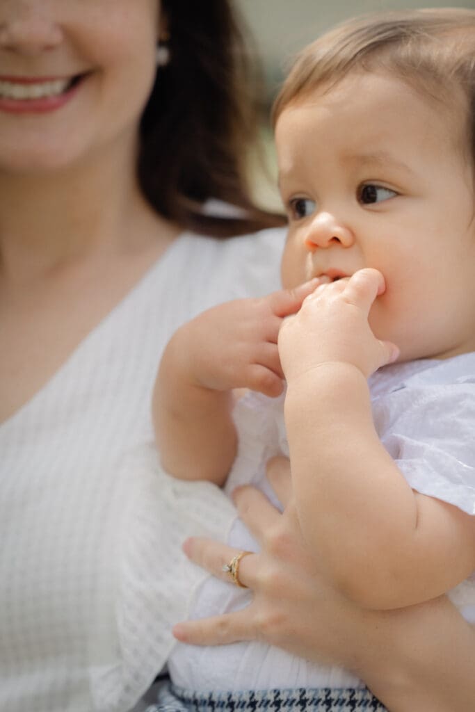 Mother holding toddler during family session as he chews on his hands
