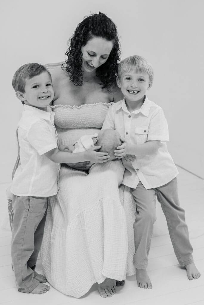 Motherhood image in black and white of a mother with her newborn and two older sons