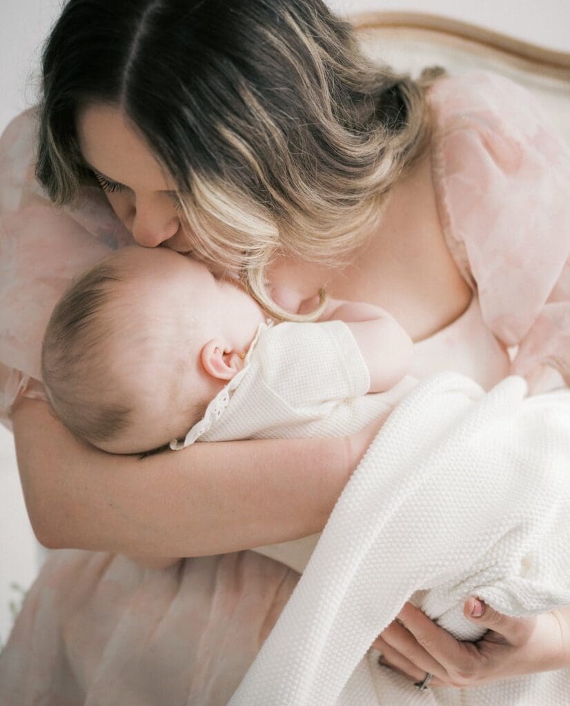 Serving women through motherhood photography by capturing a mother gently kissing her baby