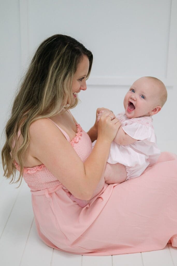 Mother sitting on the floor playing with her baby during a milestone photography session in Bainbridge, Georgia, capturing a joyful and connected moment between them