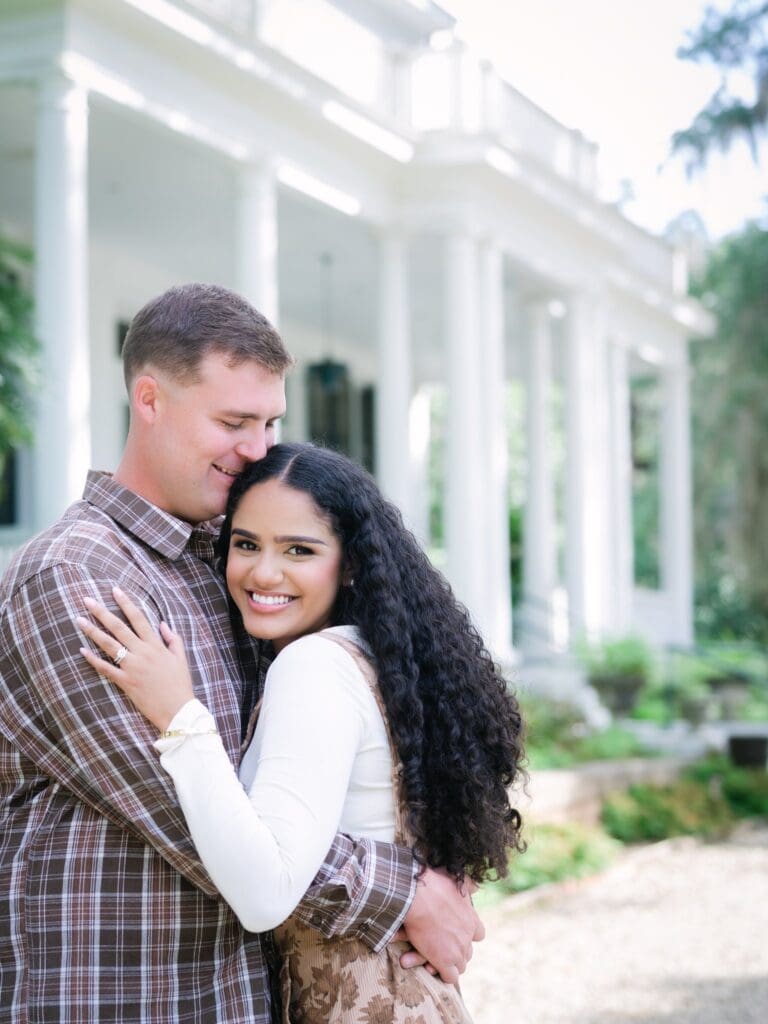 Couple hugging during anniversary session with elegant home in background