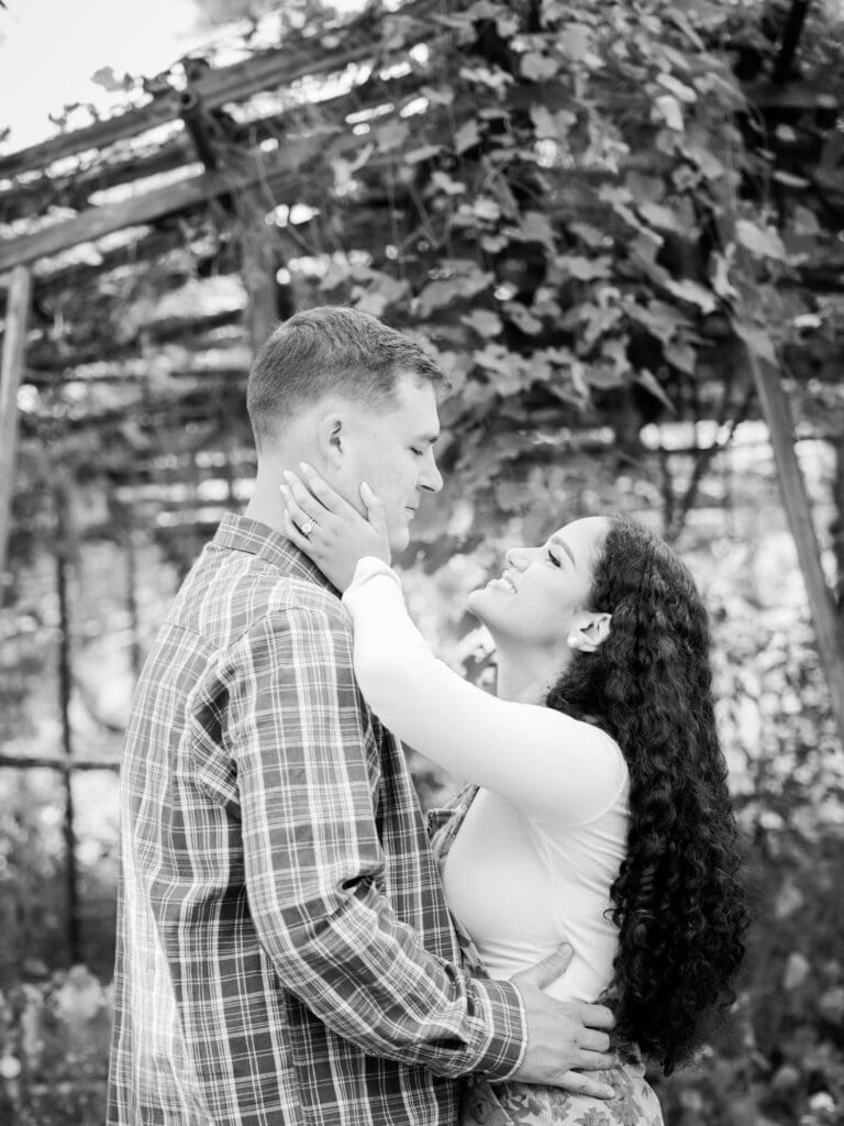 Black and white of couple smiling at each other during anniversary session in the garden