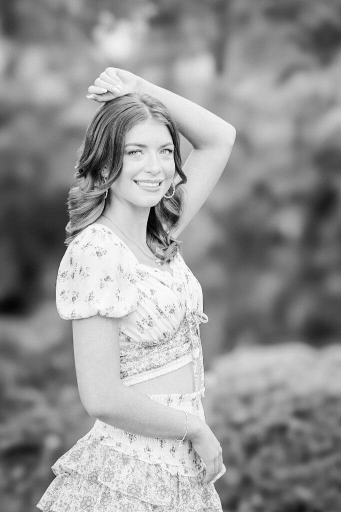 Black and white senior portrait in Bainbridge GA of girl posing with hand resting on her head in a garden