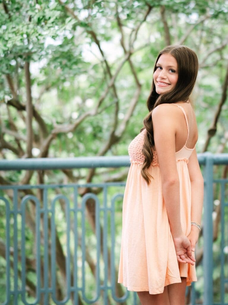 High school senior smiling over her shoulder with her hand behind her back during a senior portrait session in Tallahassee, Florida.