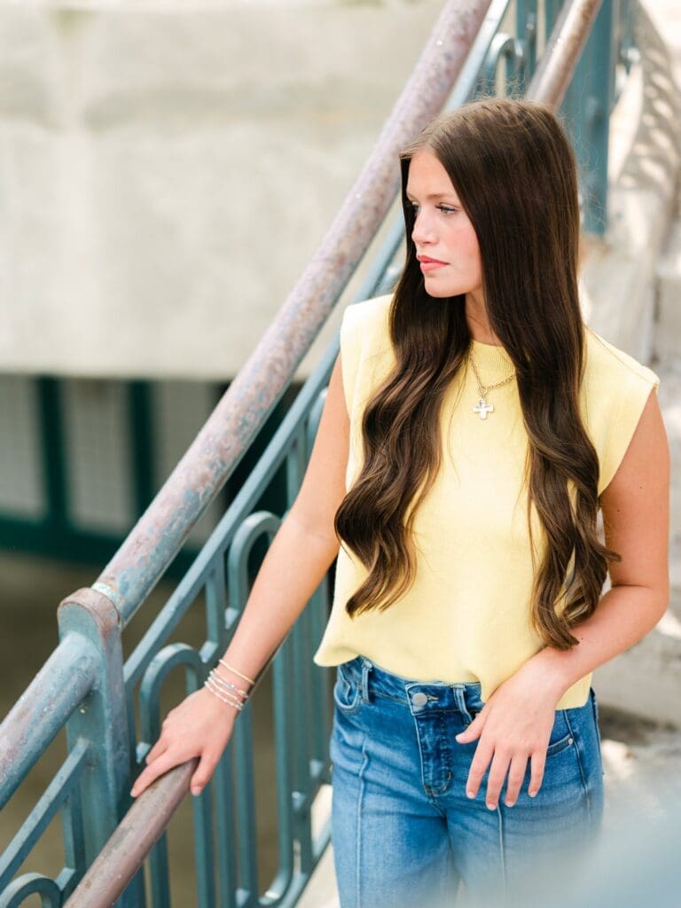 High school senior standing on an urban stairwell in Tallahassee, Florida, looking off to the side during a Class of 2027 senior portrait session.